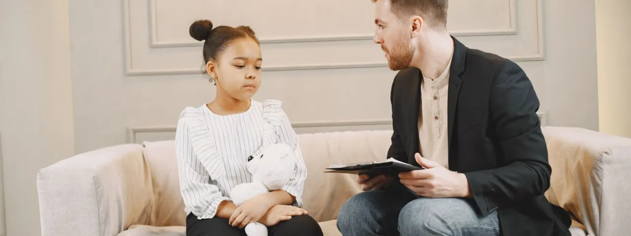Profesional conversando con una niña durante una consulta