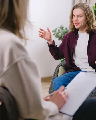 Joven hablando con su terapeuta sentado en un sofá