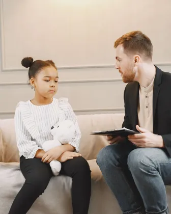 Profesional conversando con una niña durante una consulta