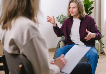 Joven hablando con su terapeuta sentado en un sofá