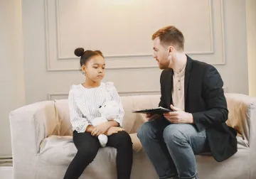 Profesional conversando con una niña durante una consulta