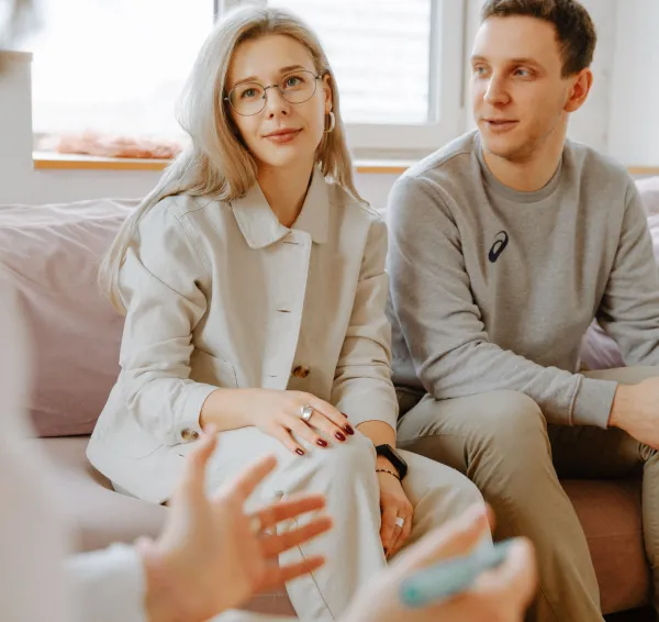 Dos personas escuchando a una terapeuta en una sesión